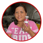 Karen - an advocate user of heartwell food supplement smiling at the camera showcasing a bottle of the product.