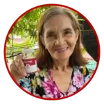 Lina - an advocate user of heartwell food supplement smiling at the camera showcasing a bottle of the product.