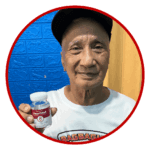 Manny - an advocate user of heartwell food supplement smiling at the camera showcasing a bottle of the product.