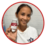 UInang - an advocate user of heartwell food supplement smiling at the camera showcasing a bottle of the product.