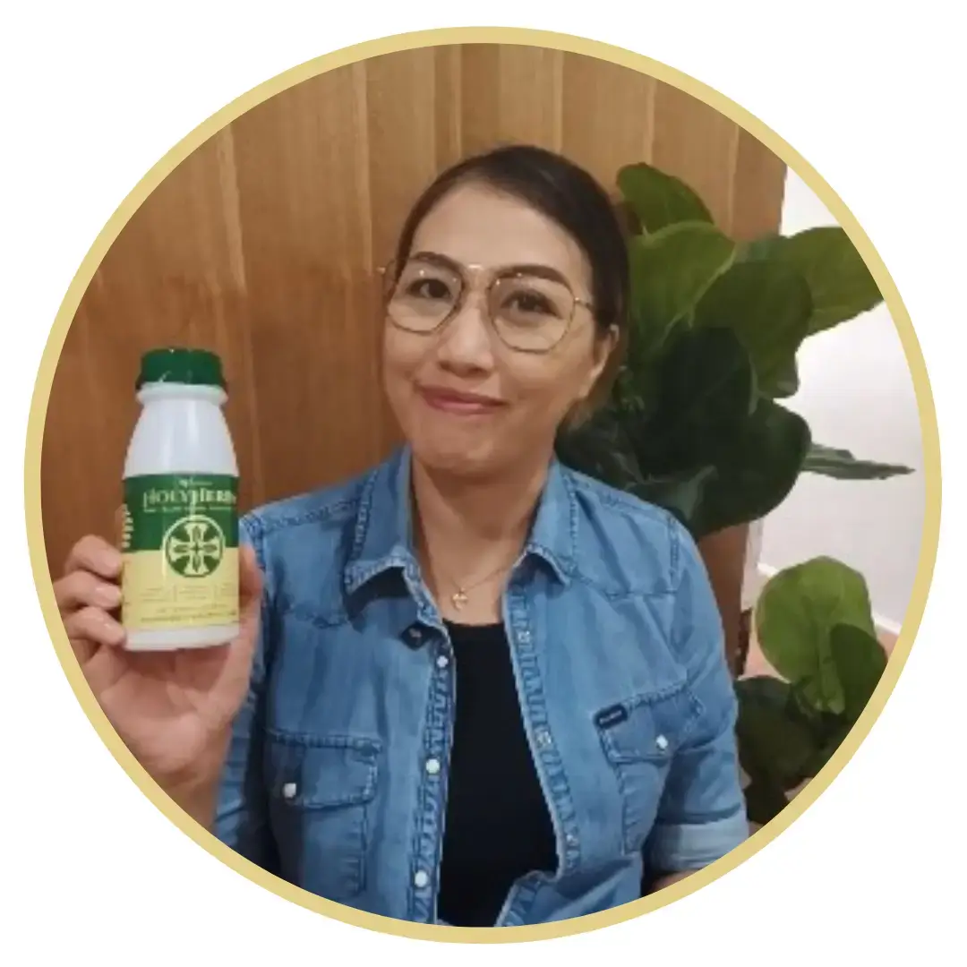 Keziah - Holy herbs advocate smiling at the camera showing the holy herbs bottle